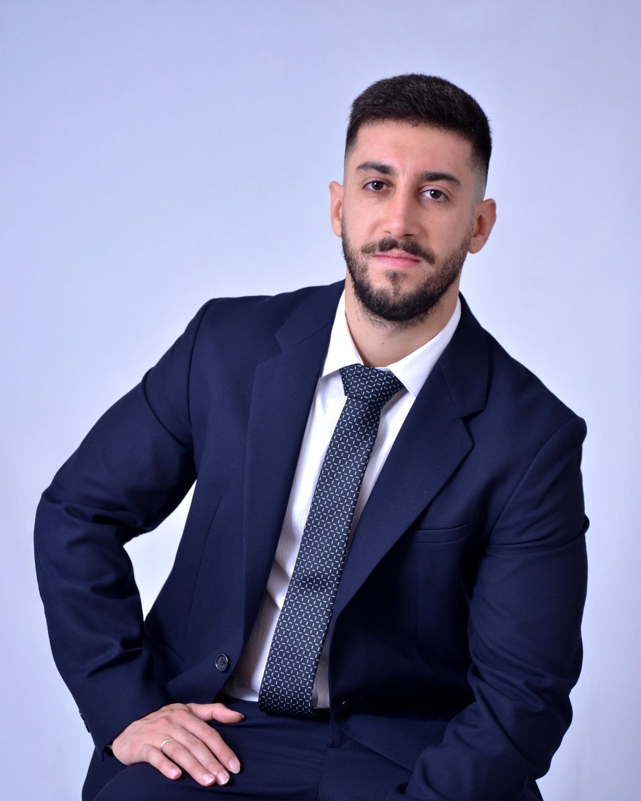 Dr. Frederico De Luca sentado, vestindo terno azul-marinho, em retrato formal de estúdio